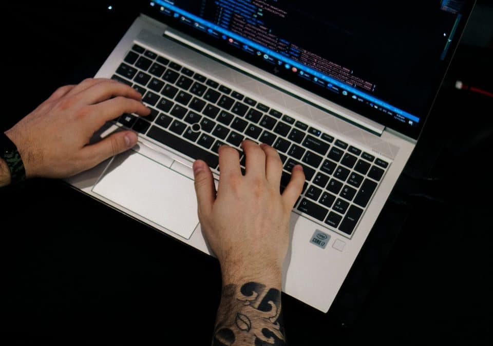 a man is typing on a laptop computer